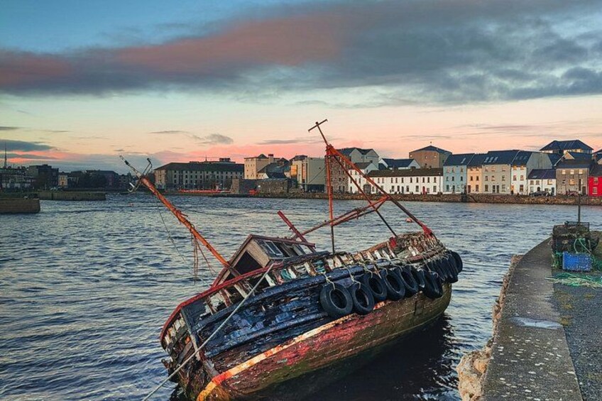 A sunken ship with a crane, water, and buildings in the background. 4