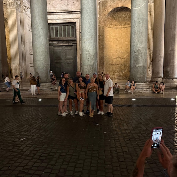 A group of people posing in front of a large, ornate door with columns. 4