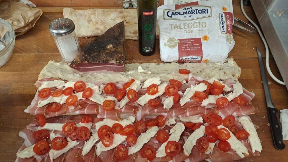 Una tabla de madera con fiambres, queso y tomates en rodajas. 2