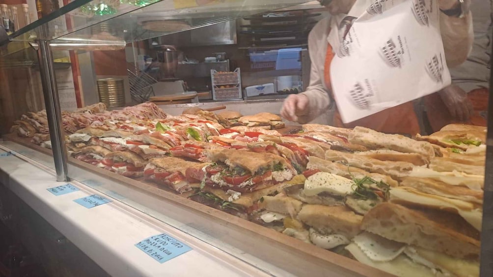 Mostrador de delicatessen con varios sándwiches exhibidos en una vitrina. 3