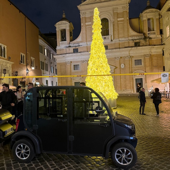 A yellow Christmas tree in front of a historic building with a car parked nearby. 4