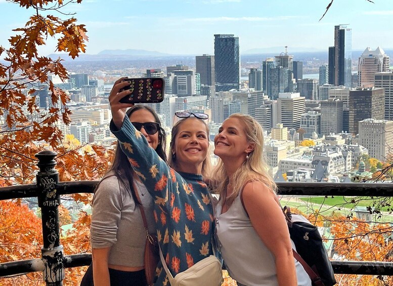Three people taking a selfie with a cityscape in the background. 1