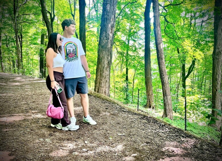Two people standing on a forest path surrounded by trees. 3