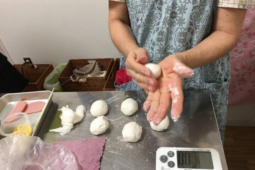 A person kneading dough on a kitchen counter. 4