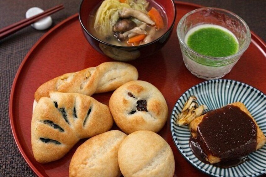 A plate with pastries, a bowl of soup, and a small dish with green sauce. 1