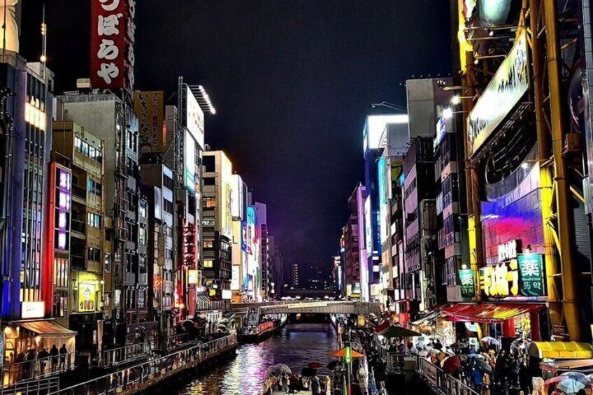 A nighttime cityscape with illuminated buildings, a river, and a bridge. 1