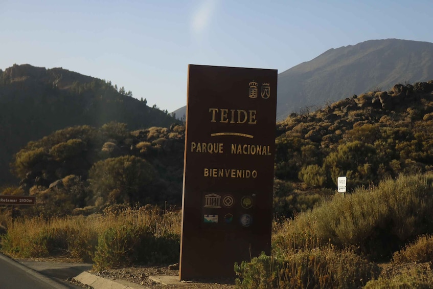 A sign for Teide National Park welcoming visitors, with a mountainous backdrop. 4