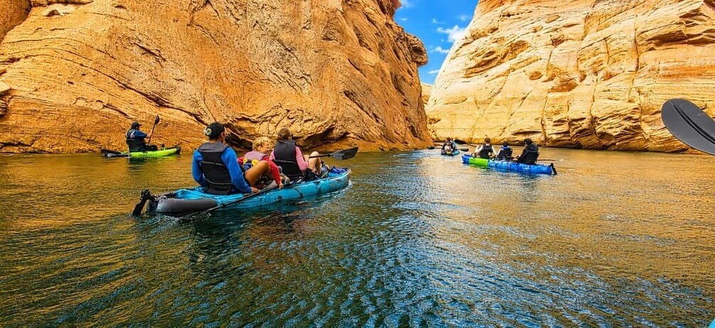 People kayaking in a canyon with clear water and rocky walls. 4