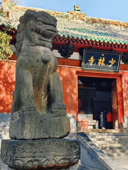 A stone lion statue in front of a traditional Chinese building with a sign that reads 'Shilin Shao'. 1