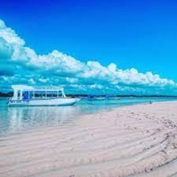A boat on a beach with clear blue water and a bright sky. 2