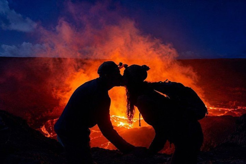 Two people in silhouette against a lava flow at night. 4