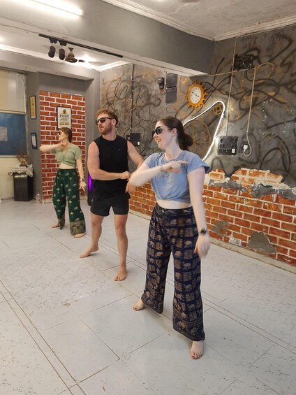 A group of people in a room with brick walls and a clock. 1