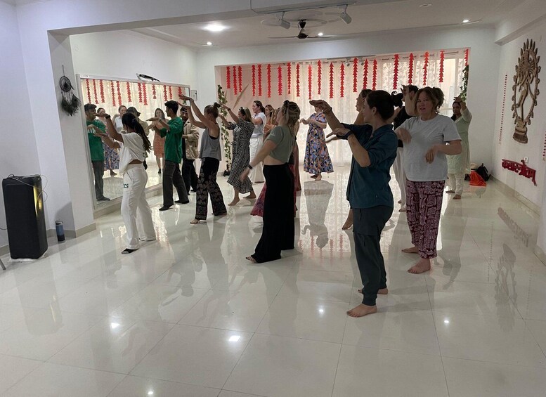 A group of people in a dance studio with a reflective floor and red decorations. 2