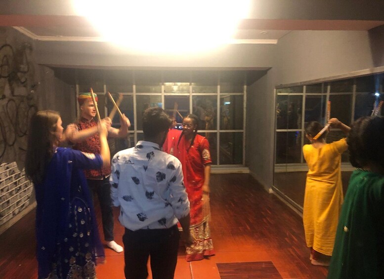 A group of people indoors, some holding sticks, in a room with wooden floors and large windows. 3