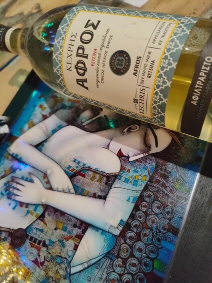 A bottle of white wine with a label featuring a woman and colorful patterns. 2