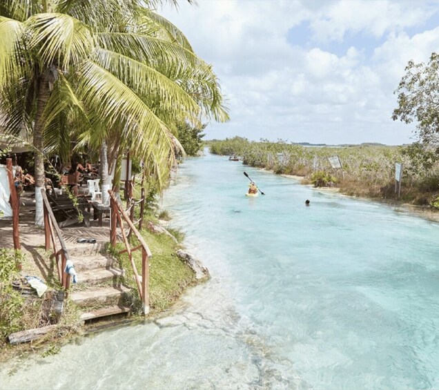 A river with clear water, a kayak, and a person paddling. 5