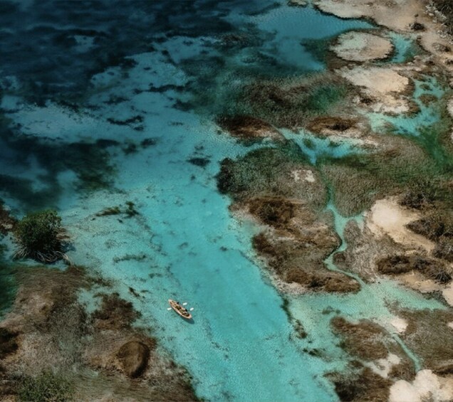 A boat on a turquoise sea with coral reefs and rocky outcrops. 4