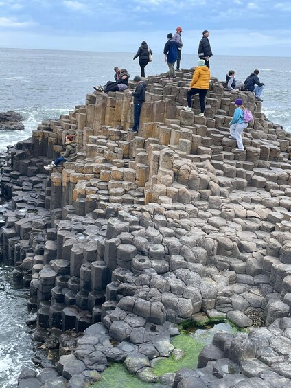 A group of people on a rocky coastal formation with the sea in the background. 1