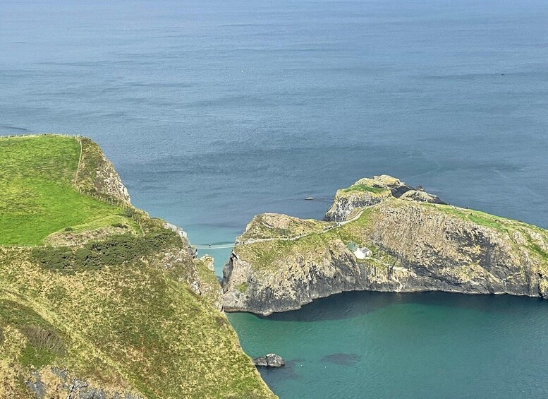 A coastal landscape with cliffs, a clear blue sea, and a small cove. 2
