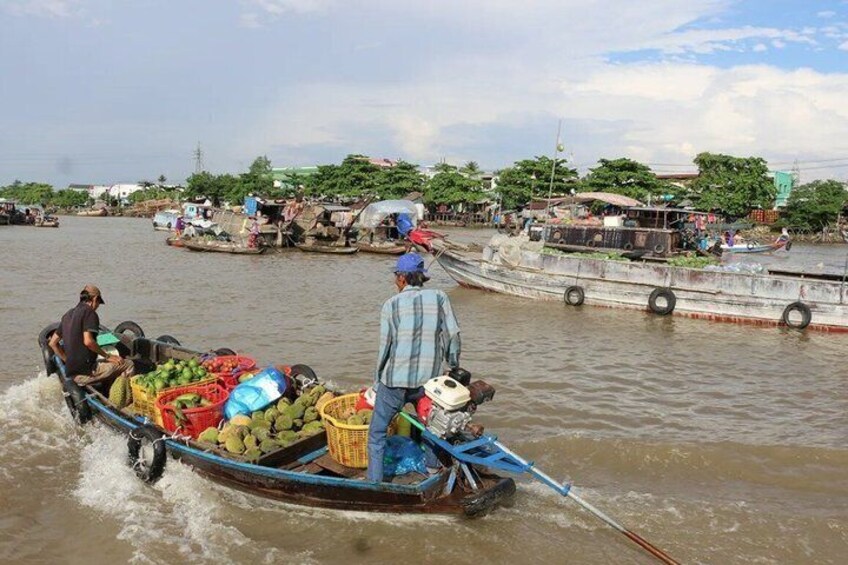 A boat carrying goods, a person rowing, and a docked boat in a river setting. 3