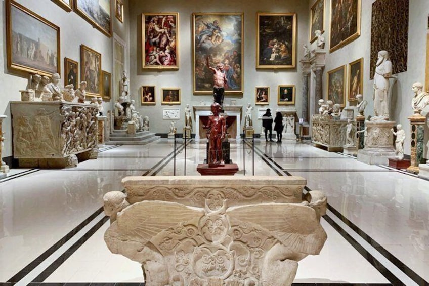 A museum interior with marble sculptures and paintings on the walls. 4