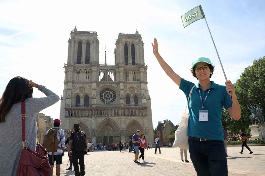 A person holding a flag with 'HOST' written on it, standing in front of a large cathedral with two towers. 4