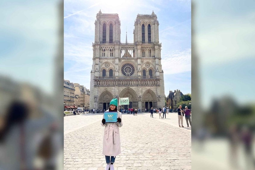 A person holding a sign in front of a large cathedral with two towers. 2