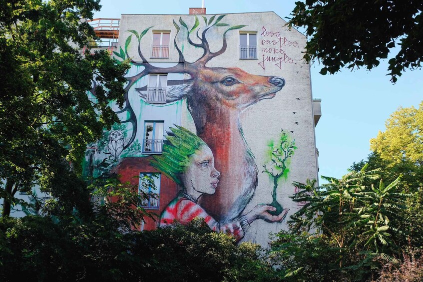 A mural of a deer and a tree on a building. 5