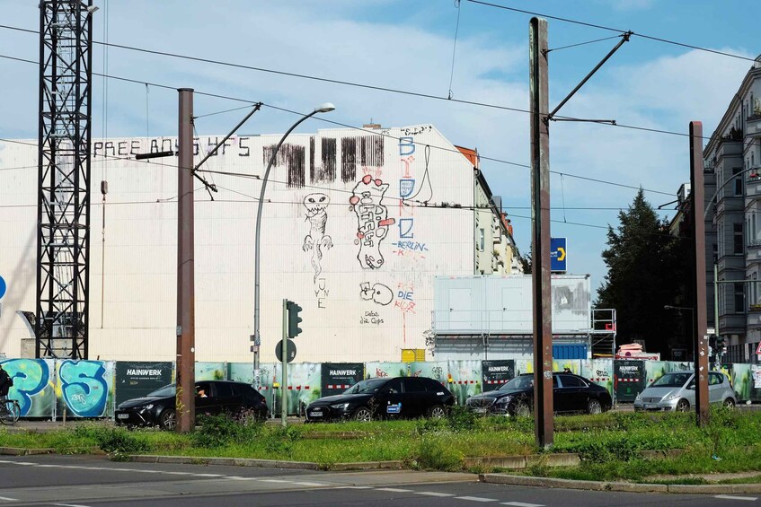 A building with graffiti, parked cars, and a traffic light. 3