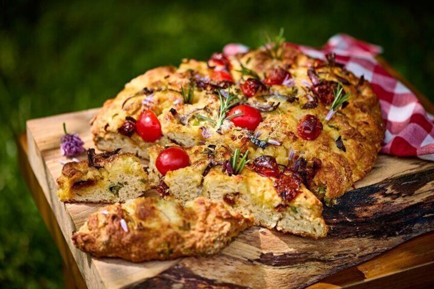 A rustic bread with tomatoes and herbs on a wooden board. 3