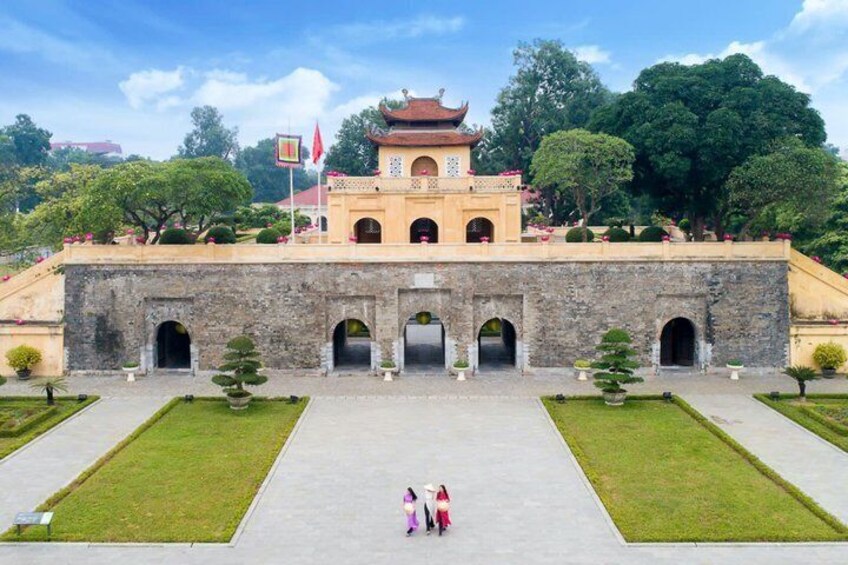 A traditional building with a tiled roof, surrounded by a symmetrical garden with neatly trimmed grass and trees. 5