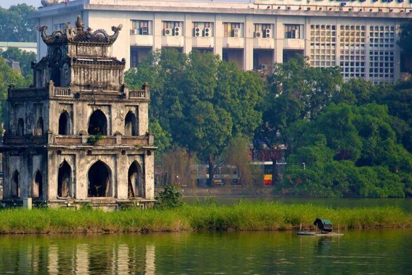 A traditional pagoda by a river with modern buildings in the background. 2