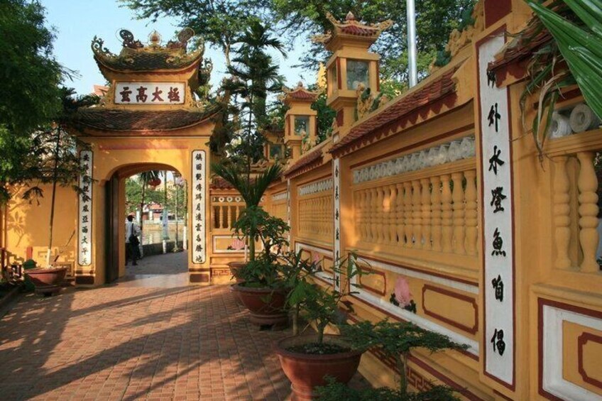 A traditional gate with Chinese characters, a tiled pathway, and potted plants. 3