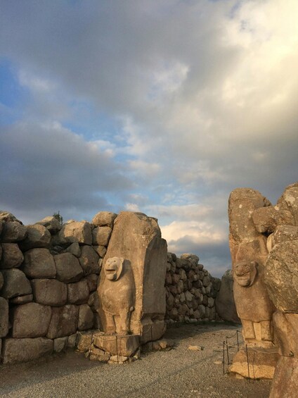 A stone wall with carved lion heads and a clear sky. 1