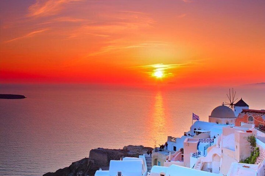 A coastal sunset with a village, white buildings, and a flag. 1