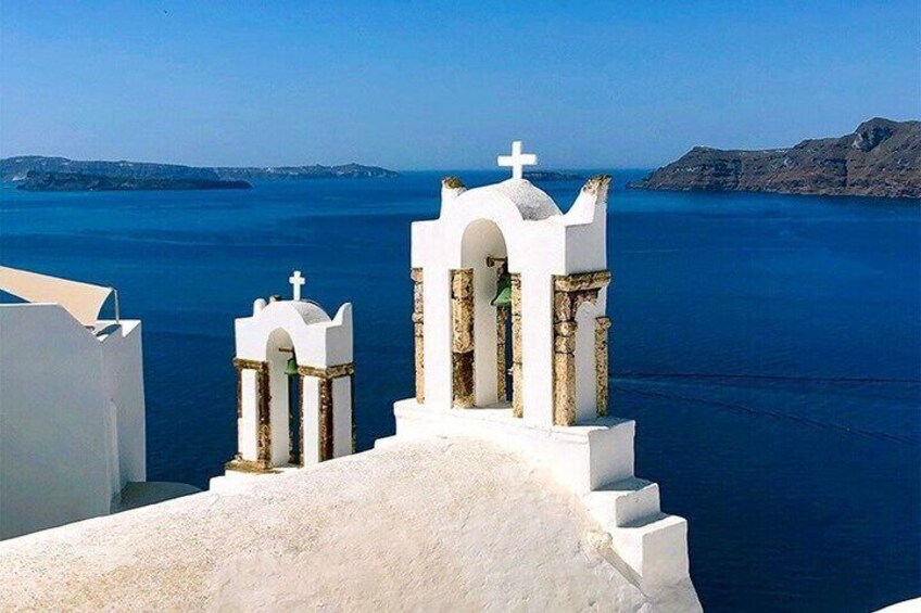 A white church with a cross on top, overlooking a deep blue sea. 2