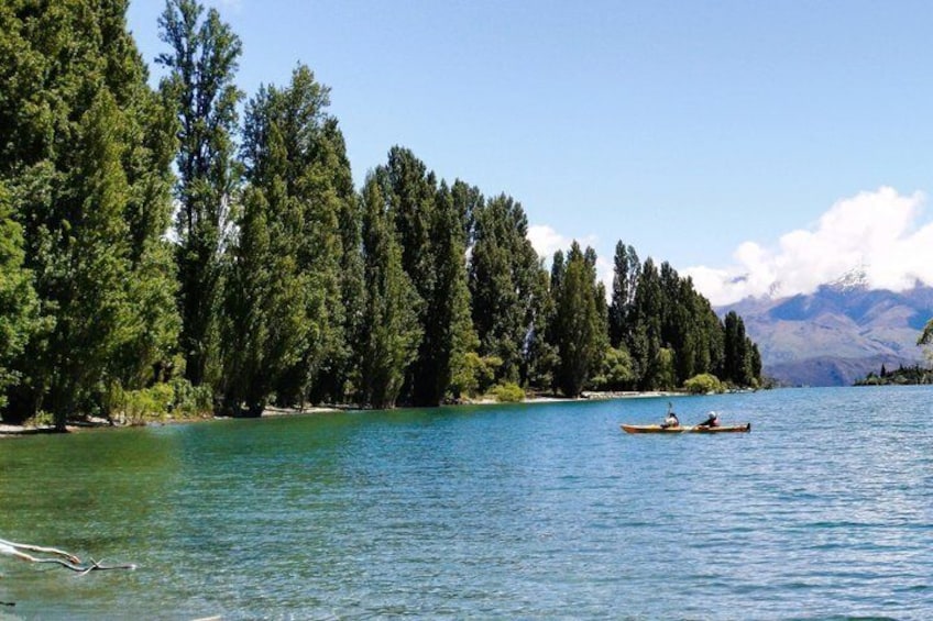 A calm lake with two canoes, dense trees, and mountains in the background. 3