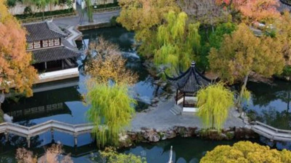 A traditional pavilion surrounded by a pond, with willow trees and autumn foliage. 5