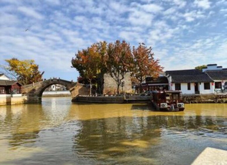 A river with a stone bridge, traditional buildings, and a boat. 4