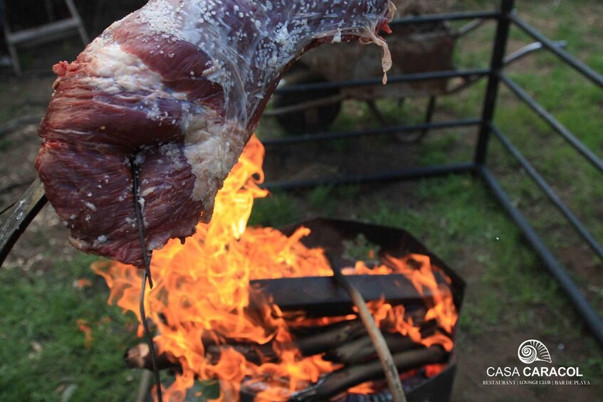 A large piece of meat being cooked over an open fire. 2