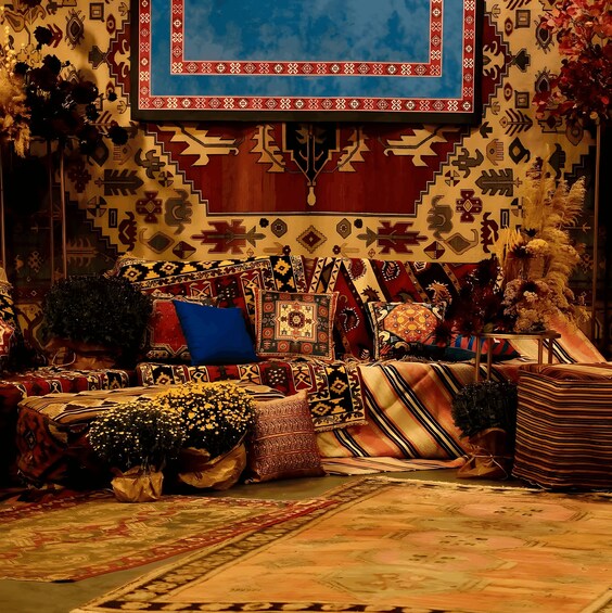 A room with patterned rugs, a blue pillow, and a decorative wall hanging. 3