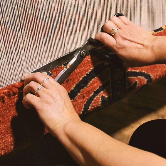 A person holding a black object with a red and black patterned fabric underneath. 5