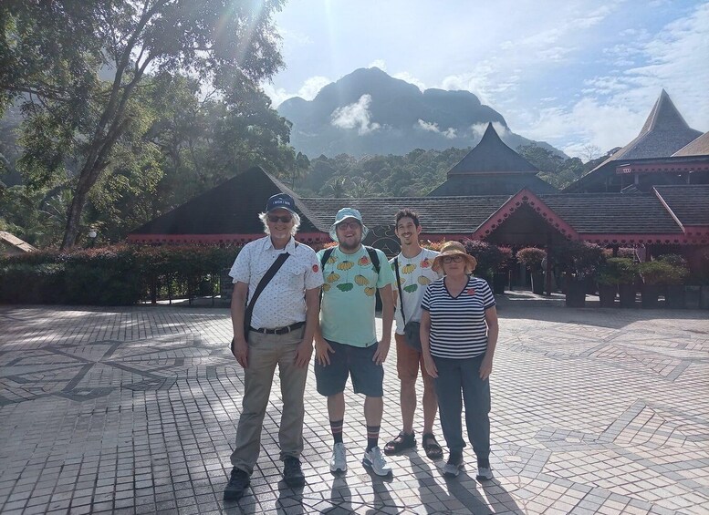 A group of people standing in front of traditional buildings with a mountainous backdrop. 1