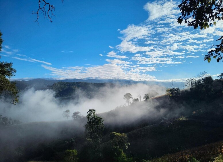 A misty landscape with a clear blue sky and scattered clouds. 3