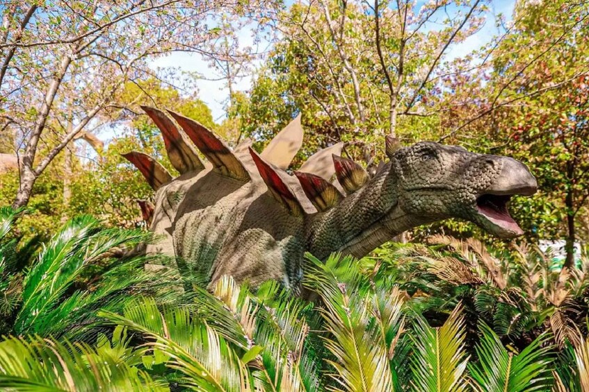 A dinosaur statue surrounded by tropical foliage. 4