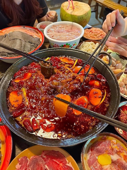 A hot pot with various meats and vegetables, surrounded by bowls of different foods. 3