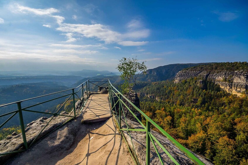 A viewpoint with a metal walkway overlooking a forested valley and distant mountains. 3