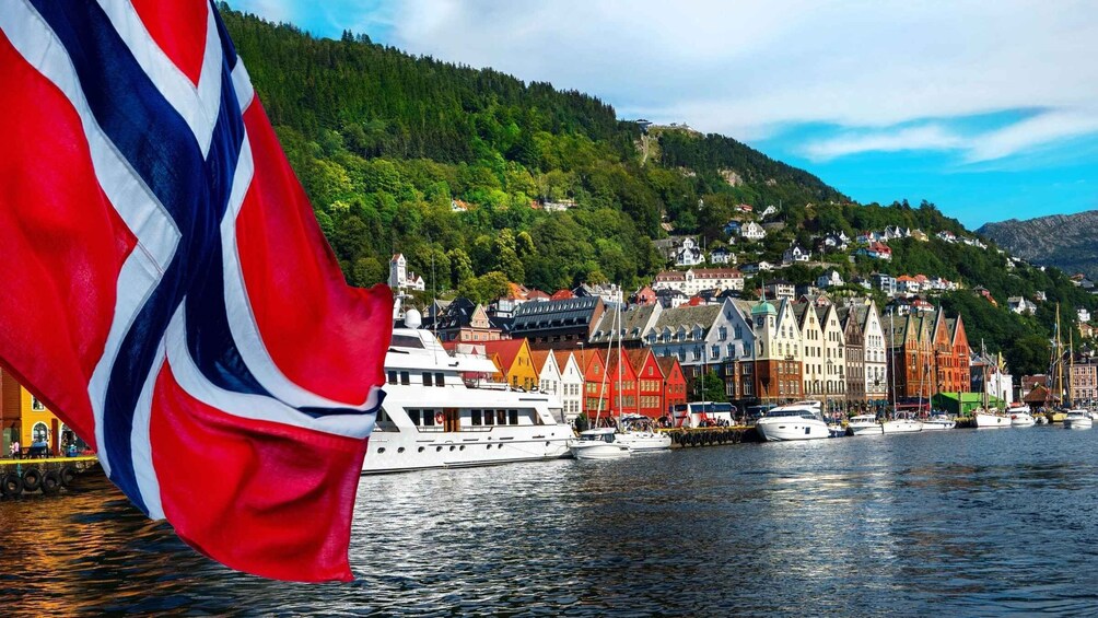 A Norwegian flag, a harbor with colorful buildings, and a forested hillside. 3