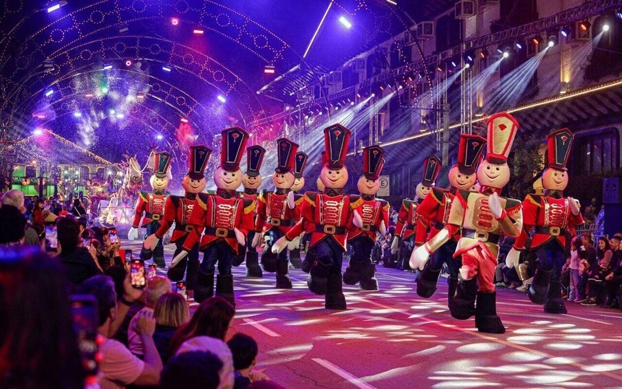 A marching band in red uniforms performing on a stage with an audience. 2
