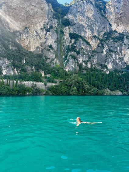 A person swimming in turquoise water with a mountainous backdrop. 3